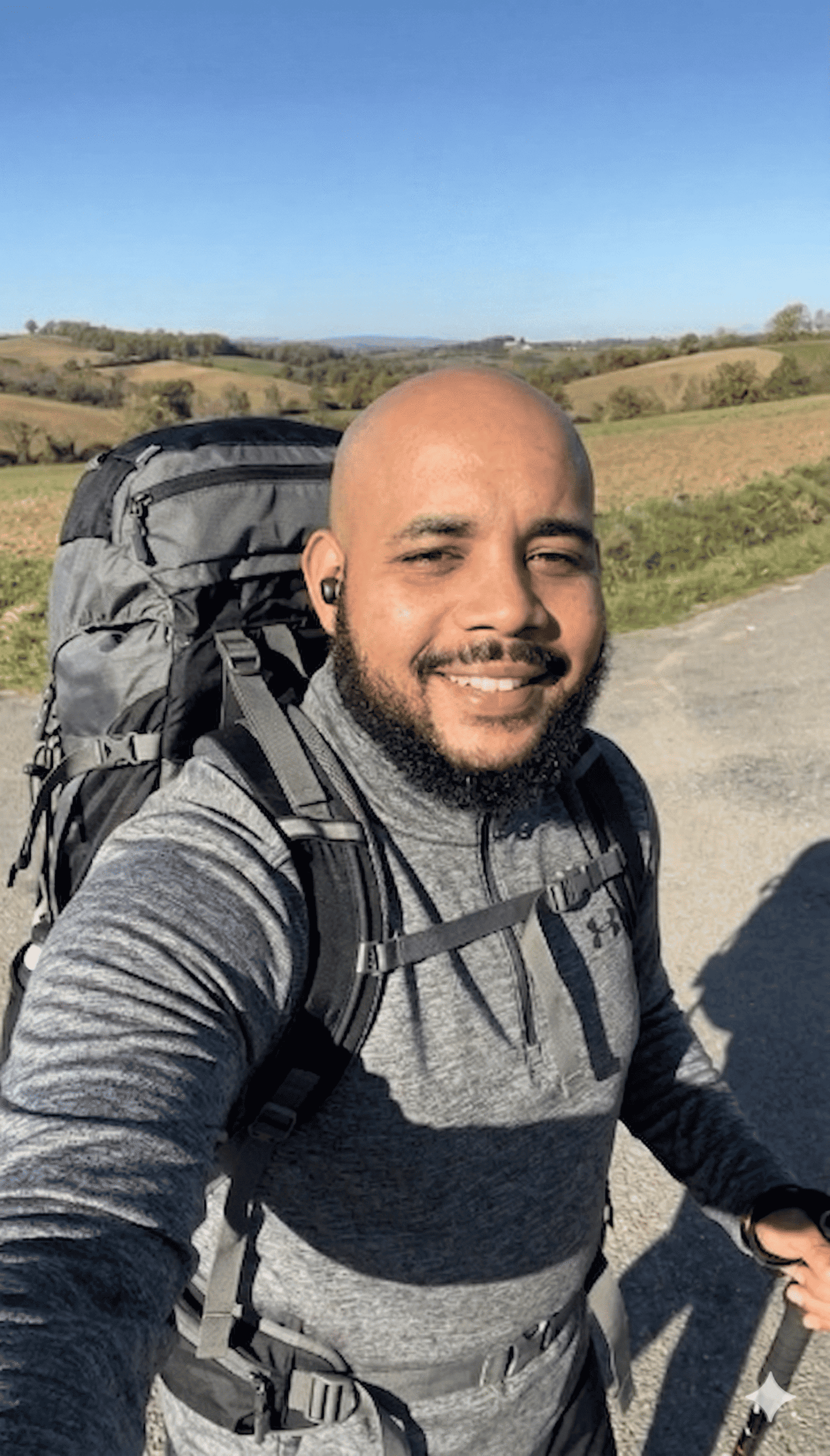 Homme avec sac à dos en randonnée dans la campagne française.